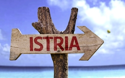 hölzernes Zeichen Istriens mit einem Strand im Hintergrund