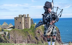 schottischer Dudelsackspieler vor Dunnottar Castle in Stonehaven