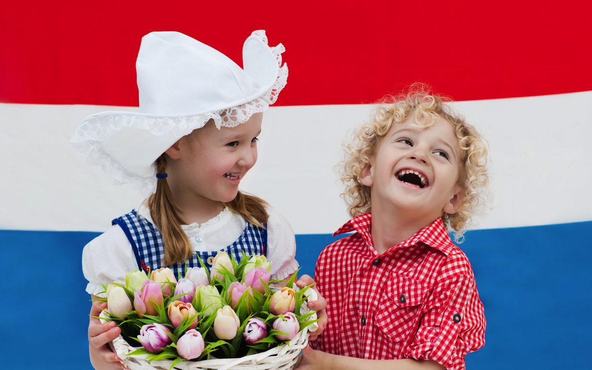 Holländische Kinder mit Tulpenblüten und niederländischer Flagge,