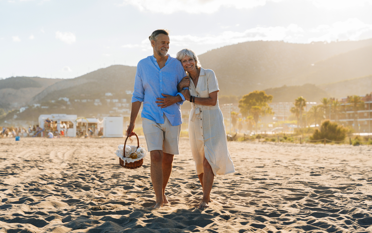 schönes, glückliches älteres Paar, das im Sommer am Meer spazieren geht