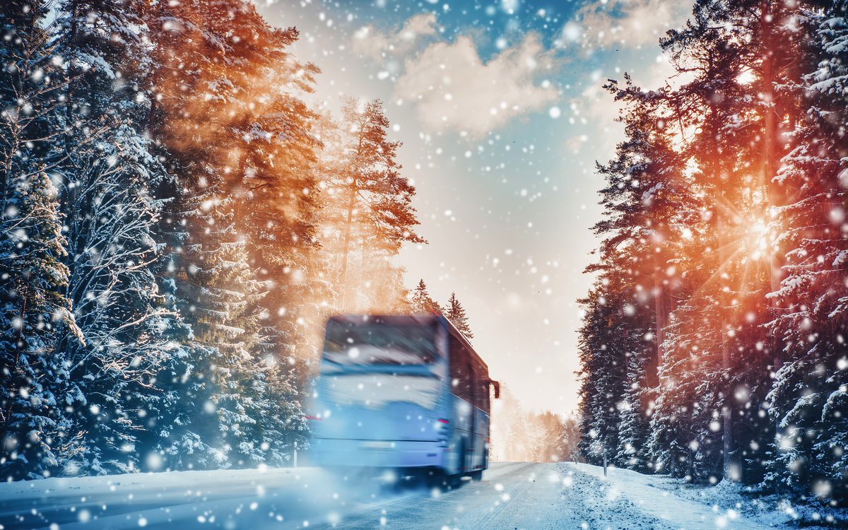 Bus auf Asphaltstraße an einem schönen Wintertag auf dem Land bei Schneefall