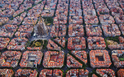 Luftaufnahme von Barcelonas schachbrettartig angelegtem Stadtviertel Eixample und der Kathedrale Sagrada Familia